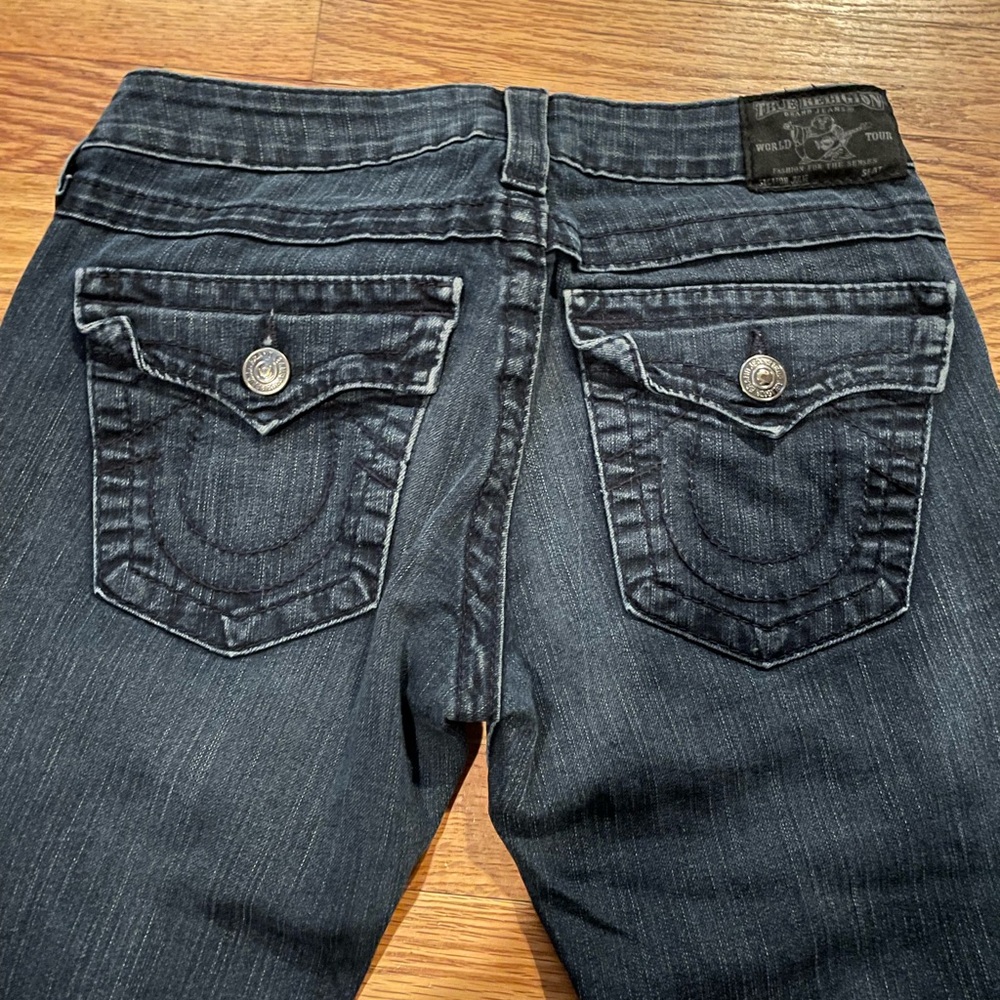 very dark wash true religion jeans with black stitching and silver buttons.